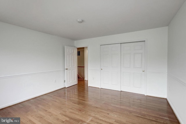 unfurnished bedroom with a closet, wood finished floors, and baseboards