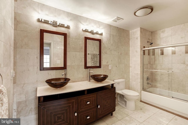 bathroom with visible vents, a sink, tile walls, and toilet