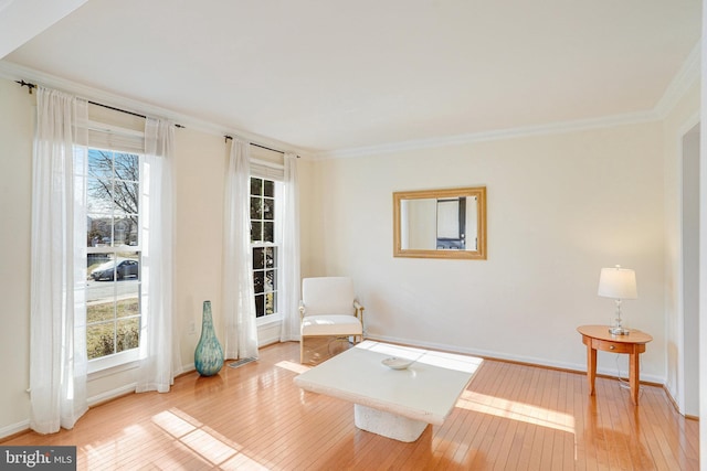 living area with wood-type flooring, baseboards, and crown molding