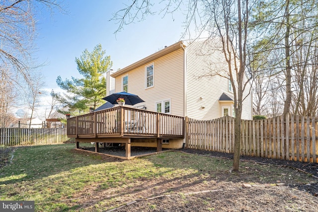 rear view of house with a fenced backyard, a lawn, and a wooden deck