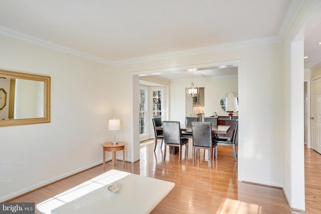 dining space featuring ornamental molding, light wood finished floors, baseboards, and a notable chandelier