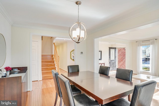 dining area with a notable chandelier, light wood-style flooring, stairway, and crown molding