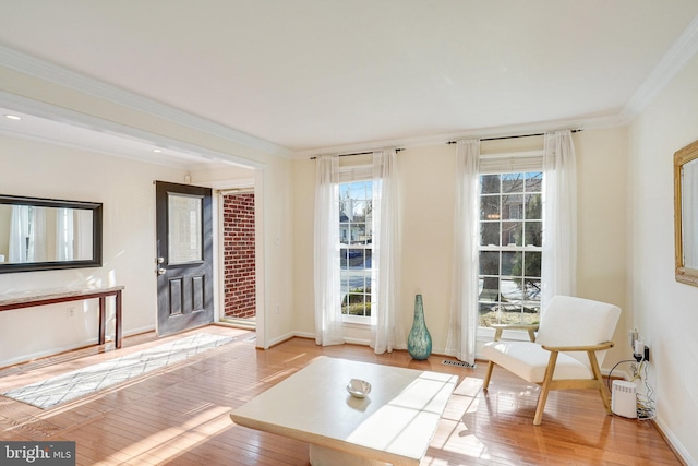 sitting room with baseboards, light wood finished floors, a wealth of natural light, and crown molding