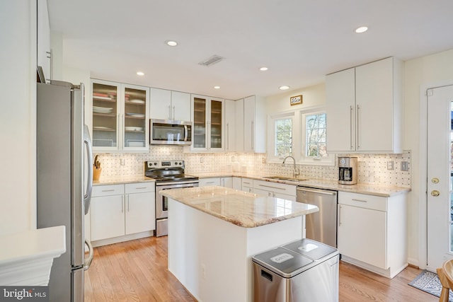 kitchen with stainless steel appliances, a sink, visible vents, and light wood-style floors