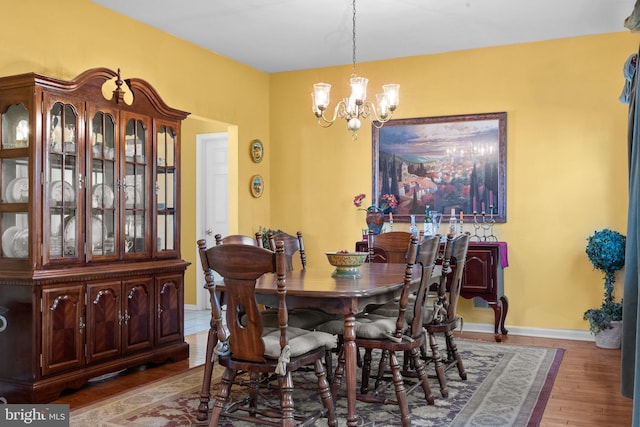 dining room featuring a notable chandelier, wood finished floors, and baseboards