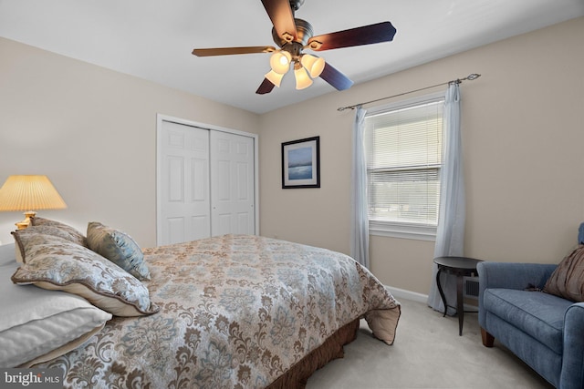 bedroom with a closet, light colored carpet, baseboards, and a ceiling fan