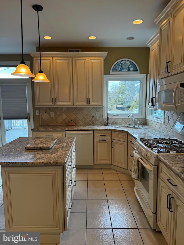 kitchen featuring white appliances, visible vents, a sink, cream cabinetry, and backsplash