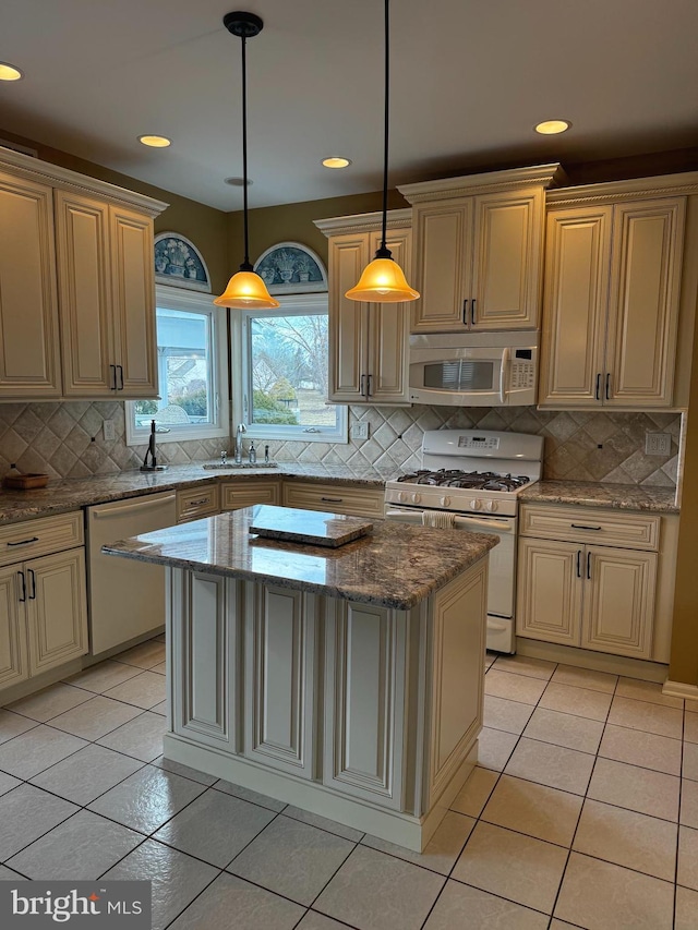 kitchen with cream cabinetry, a sink, a center island, white appliances, and light tile patterned floors