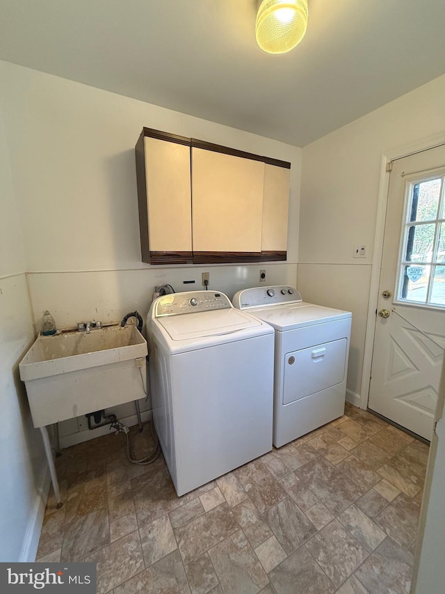 clothes washing area featuring stone finish floor, a sink, cabinet space, and washer and dryer