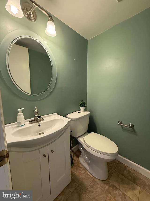 bathroom featuring toilet, baseboards, and vanity