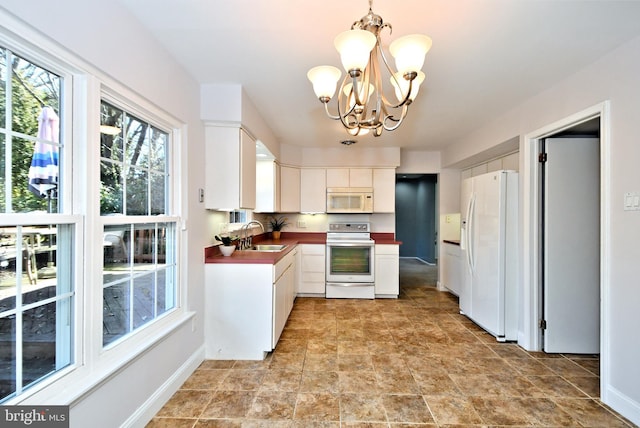 kitchen featuring a notable chandelier, white cabinets, a sink, white appliances, and baseboards