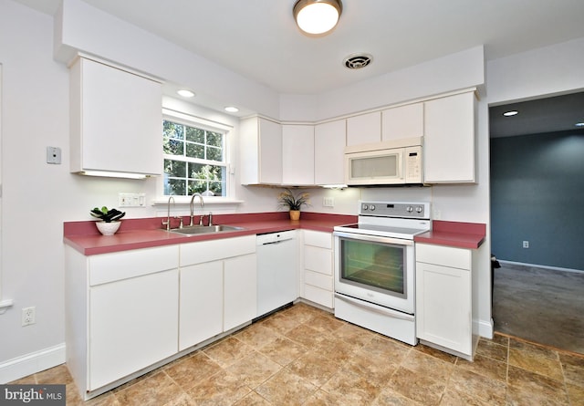 kitchen with white appliances, a sink, visible vents, baseboards, and white cabinets