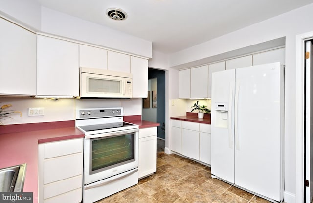 kitchen featuring white appliances, visible vents, dark countertops, white cabinetry, and a sink