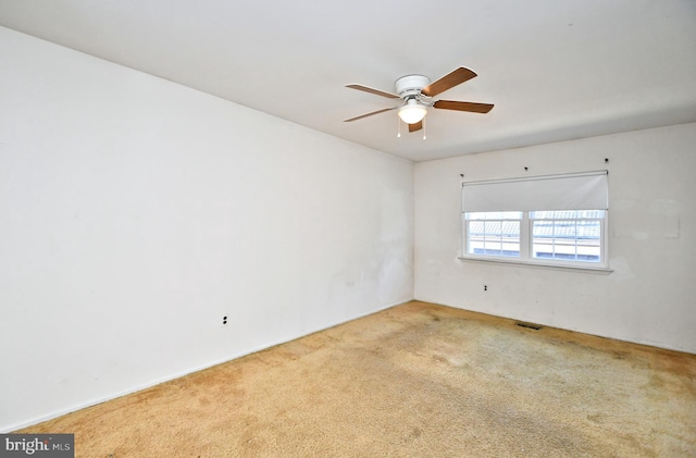 carpeted spare room featuring ceiling fan and visible vents