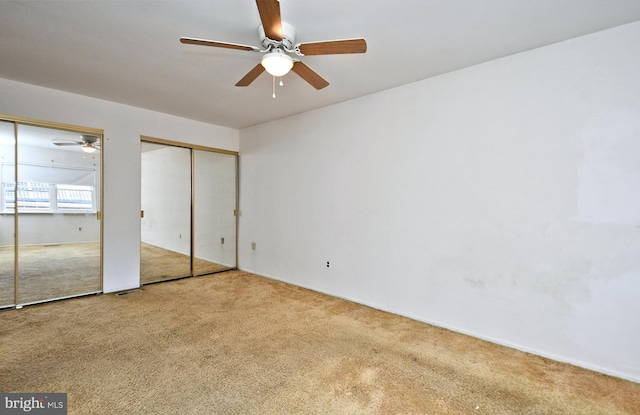 unfurnished bedroom with carpet flooring, visible vents, and multiple closets