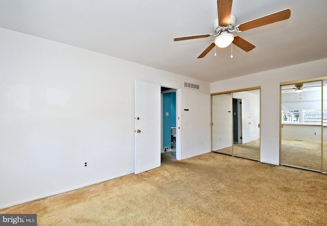 unfurnished bedroom with multiple closets, visible vents, ceiling fan, and carpet floors