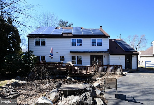 rear view of house with a deck and roof mounted solar panels