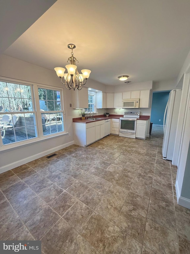 kitchen with white appliances, white cabinetry, baseboards, and a sink