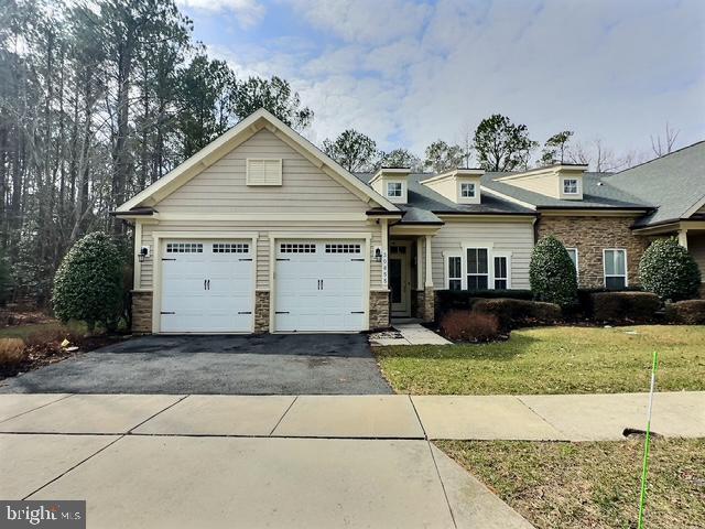 view of front of home featuring aphalt driveway, a garage, stone siding, and a front lawn