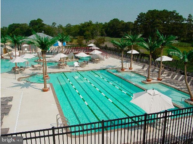 community pool with a patio area and fence