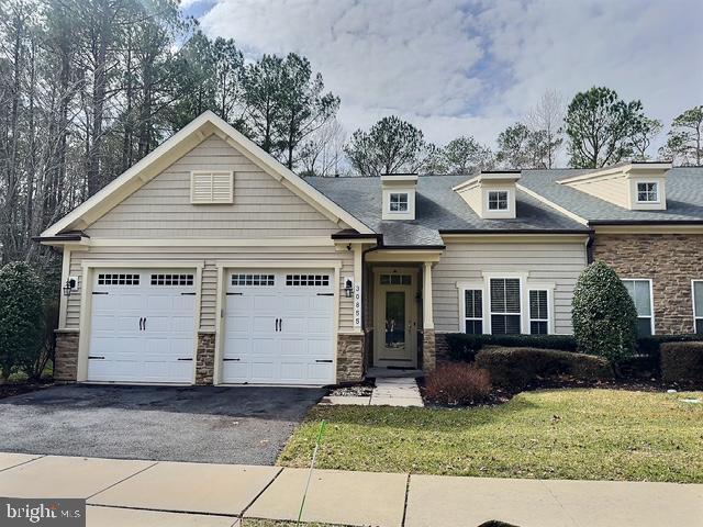 view of front of property with a front yard, an attached garage, stone siding, and driveway