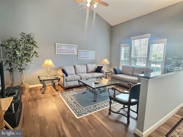 living room with ceiling fan, wood finished floors, baseboards, and high vaulted ceiling