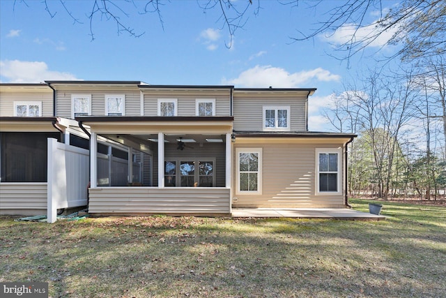 rear view of property featuring a lawn, a ceiling fan, a patio, and a sunroom