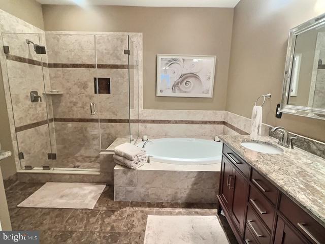 full bathroom featuring vanity, a garden tub, and a stall shower