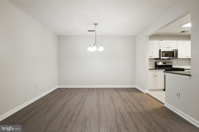 interior space featuring a chandelier, visible vents, baseboards, and wood finished floors