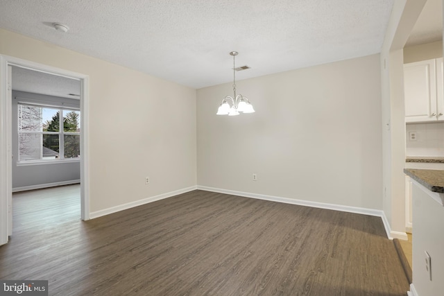 unfurnished dining area with baseboards, a notable chandelier, visible vents, and dark wood-style flooring