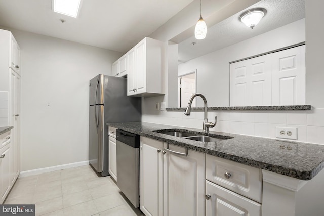 kitchen with a sink, white cabinetry, stainless steel dishwasher, backsplash, and dark stone countertops