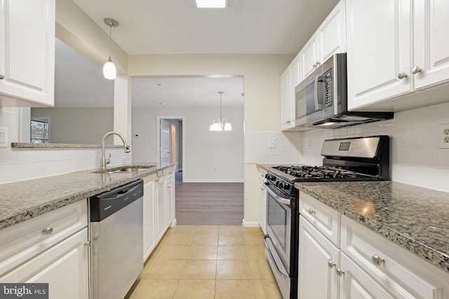 kitchen featuring light tile patterned floors, stainless steel appliances, a sink, white cabinets, and decorative backsplash