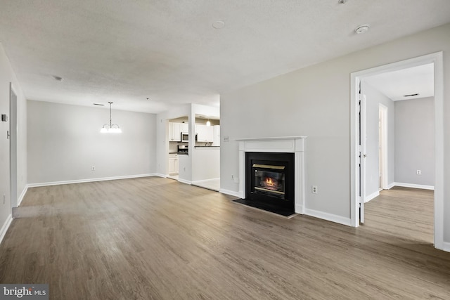 unfurnished living room featuring a fireplace with flush hearth, baseboards, and wood finished floors