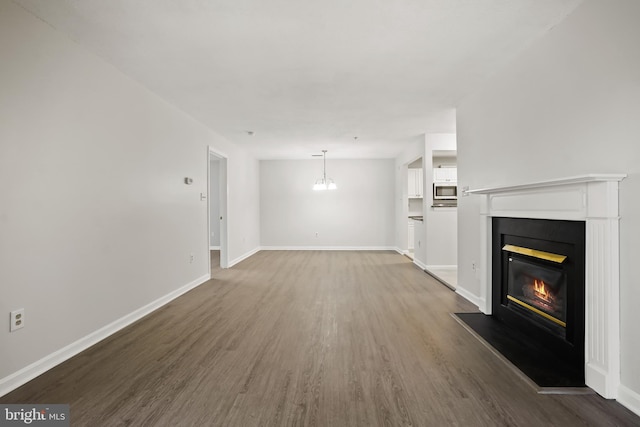 unfurnished living room with a glass covered fireplace, baseboards, and wood finished floors