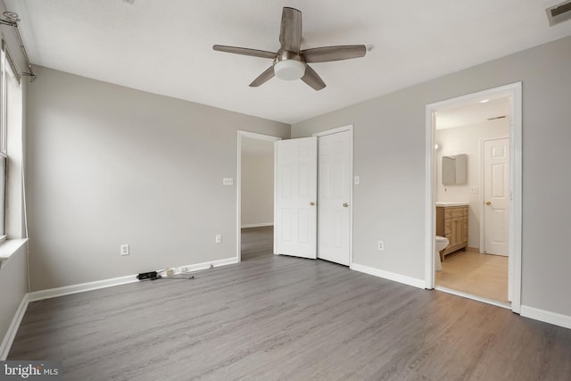 unfurnished bedroom featuring wood finished floors, a ceiling fan, visible vents, baseboards, and ensuite bath