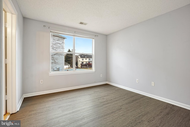 unfurnished room featuring a textured ceiling, wood finished floors, visible vents, and baseboards