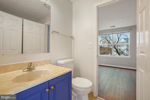 bathroom featuring a textured ceiling, wood finished floors, vanity, and toilet