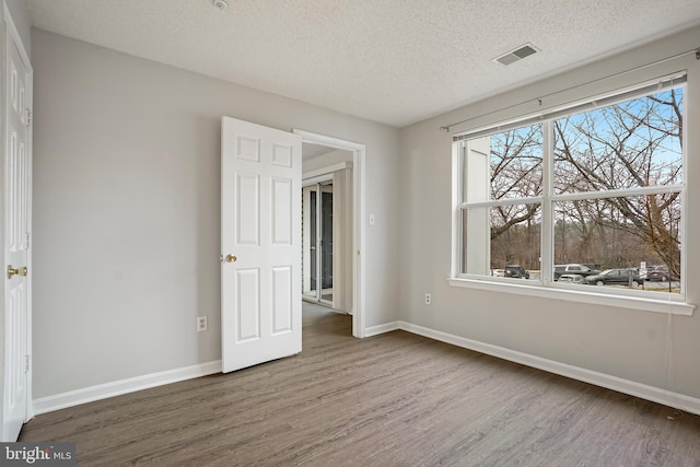 unfurnished bedroom featuring wood finished floors, visible vents, and baseboards