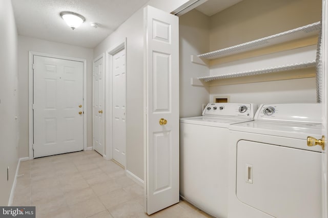 laundry area featuring washer and dryer, laundry area, a textured ceiling, and baseboards