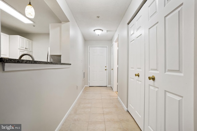 hallway with light tile patterned flooring and baseboards