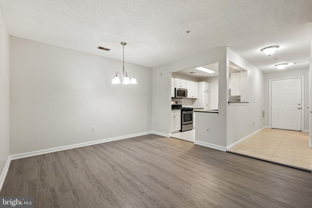 unfurnished living room featuring visible vents, light wood-style flooring, and baseboards