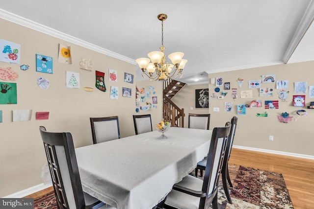 dining space with wood finished floors, crown molding, baseboards, a chandelier, and stairs