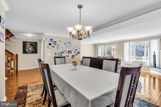 dining area with a chandelier, baseboards, ornamental molding, and light wood finished floors