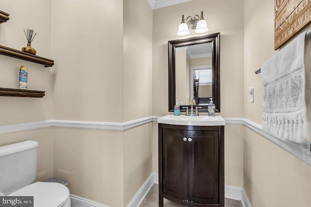 half bath with crown molding, toilet, vanity, and baseboards