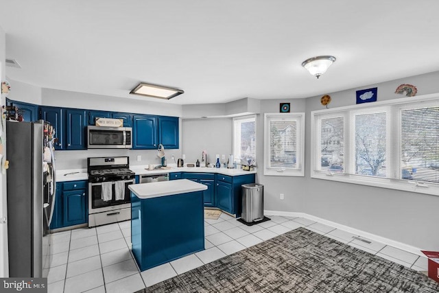 kitchen with blue cabinets, light tile patterned floors, and stainless steel appliances