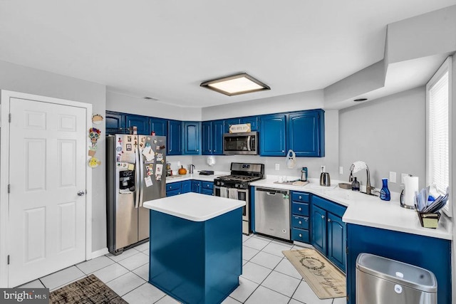 kitchen with light tile patterned floors, blue cabinetry, a sink, light countertops, and appliances with stainless steel finishes