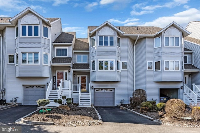 multi unit property with aphalt driveway, an attached garage, and a shingled roof