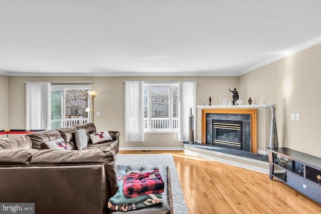 living room featuring a premium fireplace, crown molding, baseboards, and wood finished floors