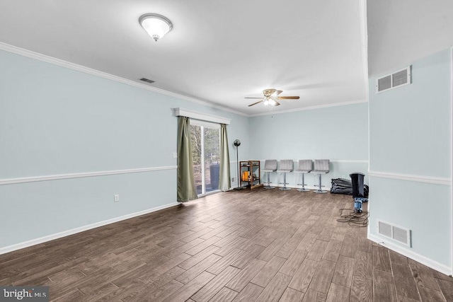 interior space featuring visible vents, crown molding, baseboards, and wood finished floors