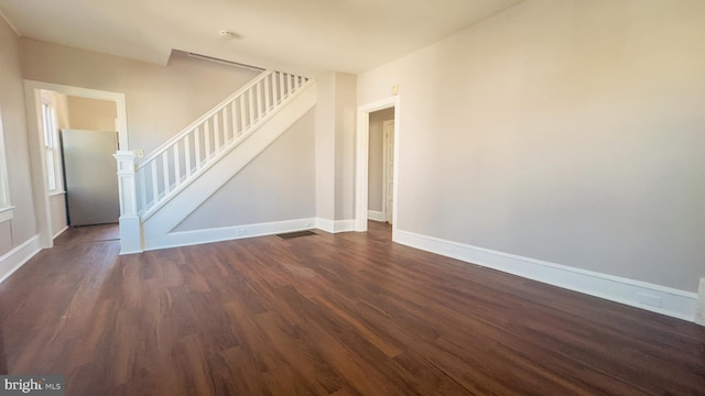 spare room with stairs, dark wood finished floors, visible vents, and baseboards